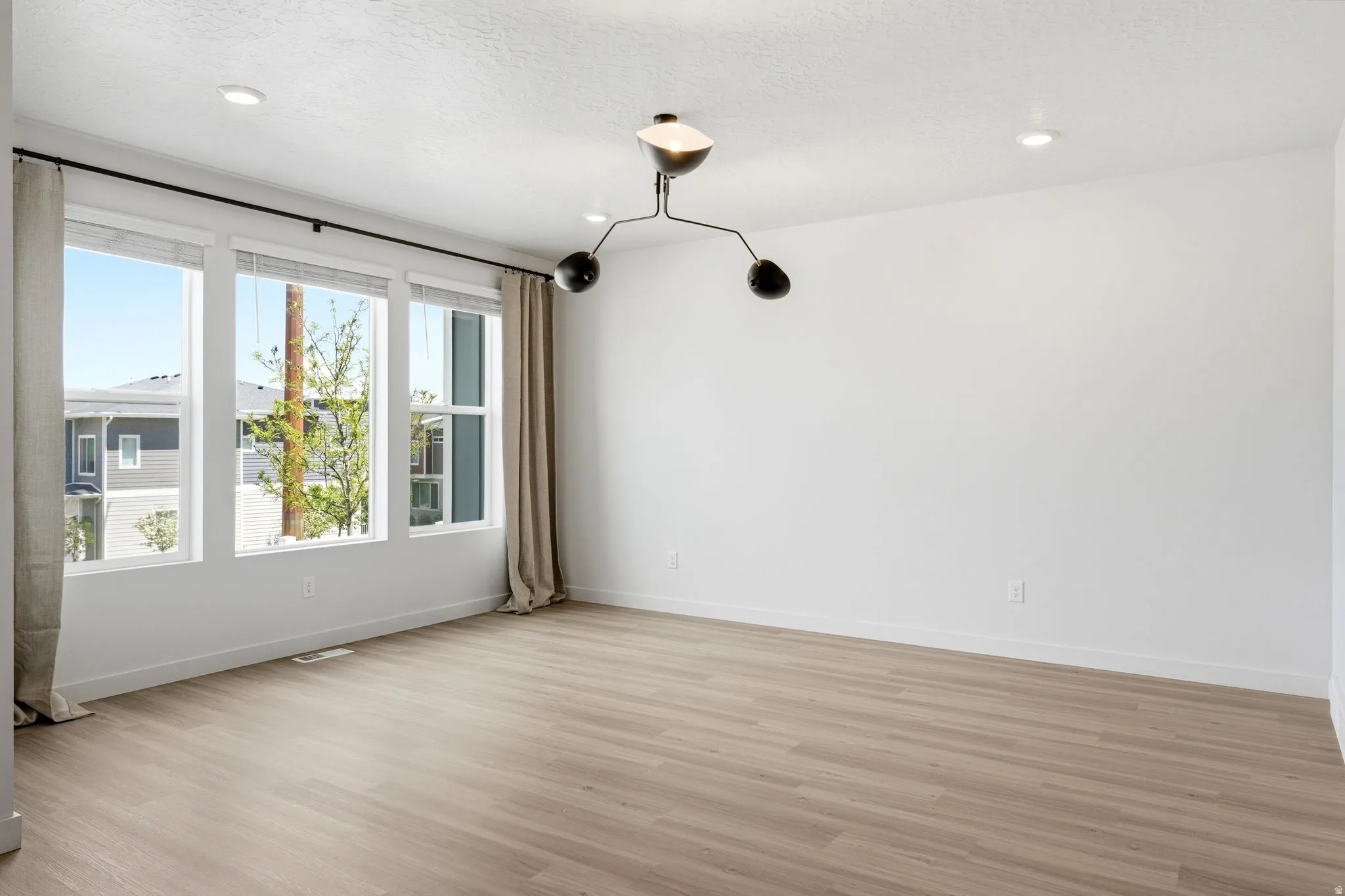 Light wood-finish flooring complements the crisp white walls and contemporary black chandelier