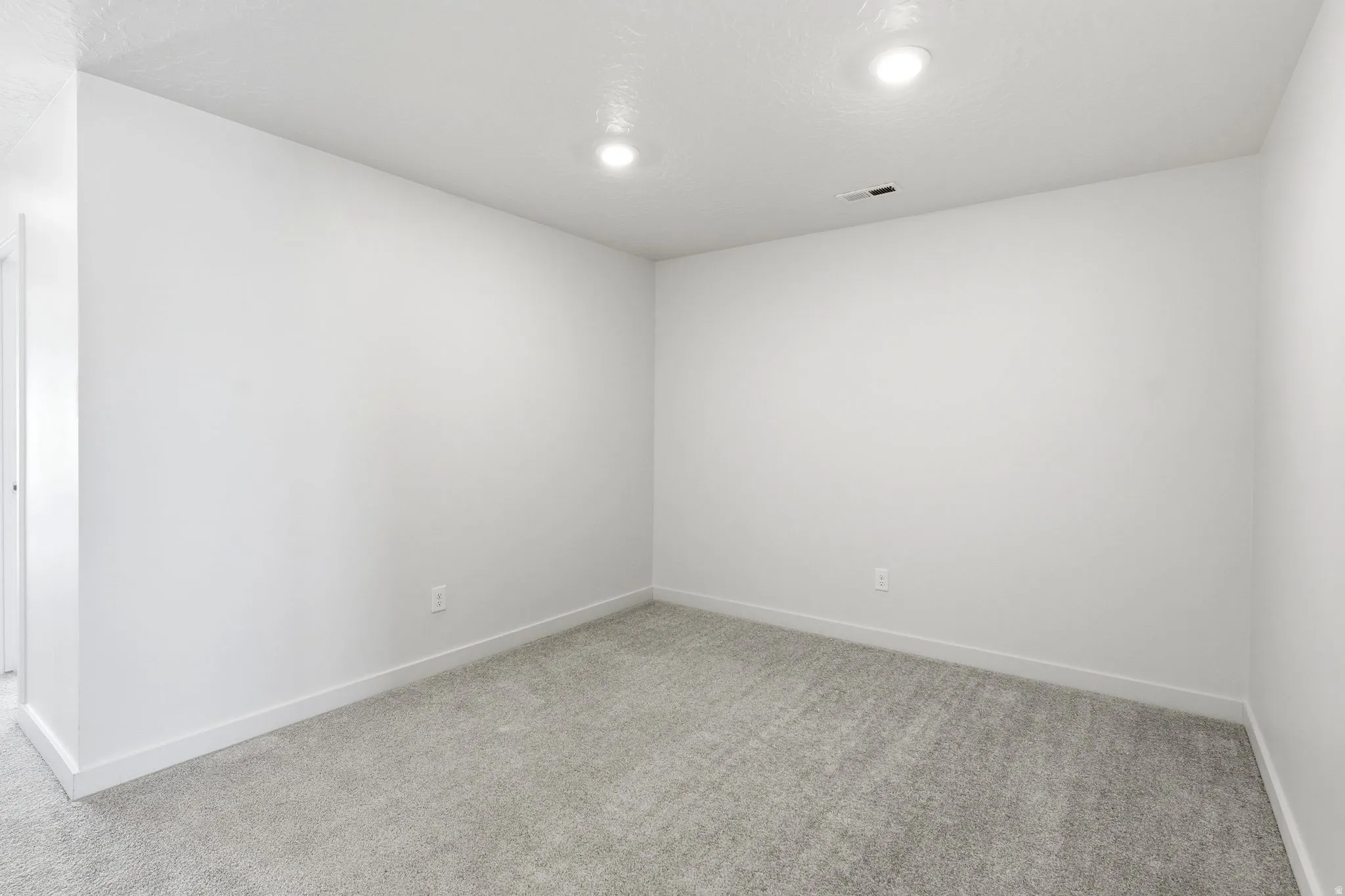 Neutral-toned room featuring light gray carpeting, white painted walls, and recessed ceiling lighting