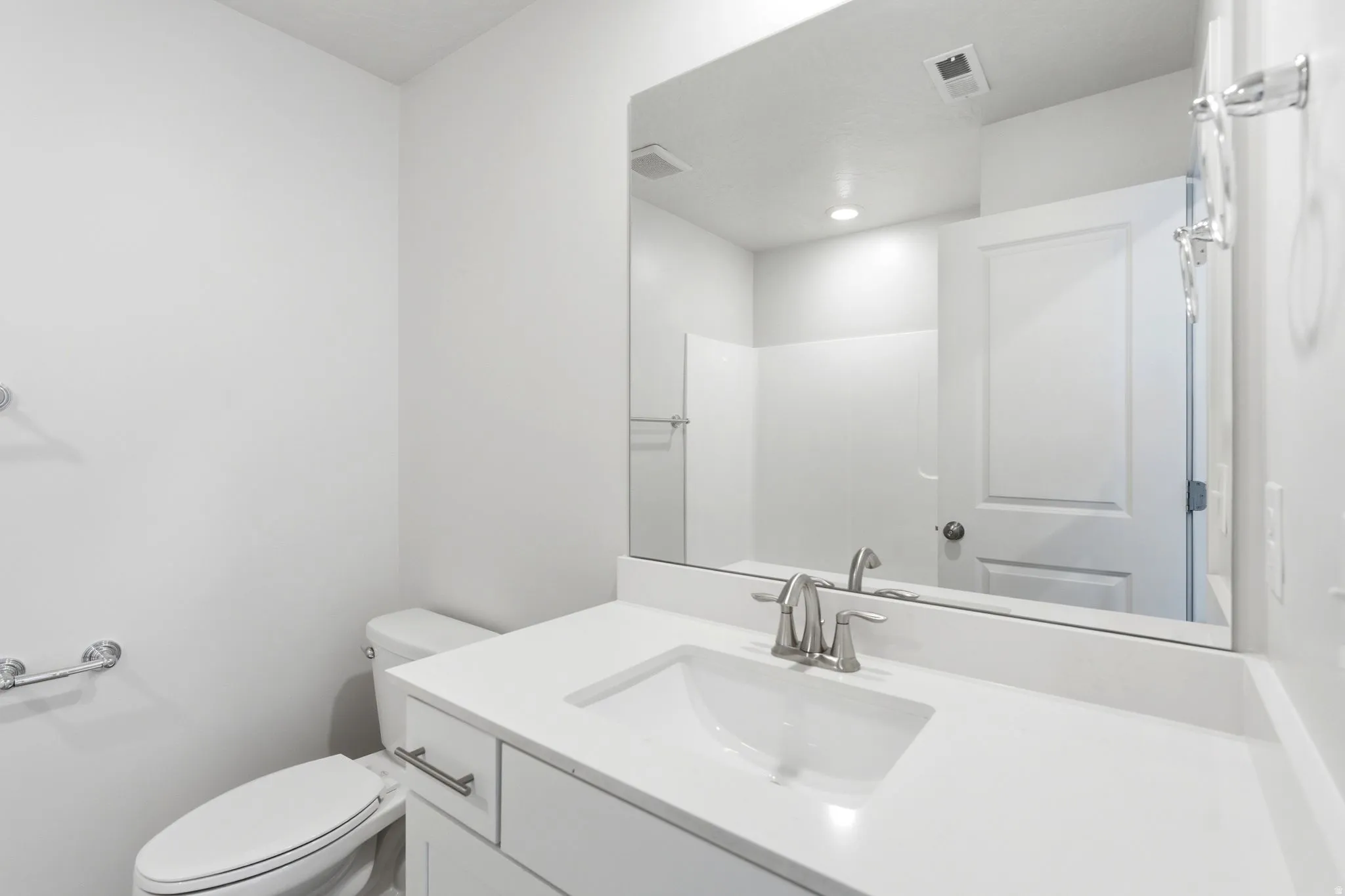 Bathroom featuring a white vanity with an integrated sink, polished chrome faucet, and expansive wall-mounted mirror