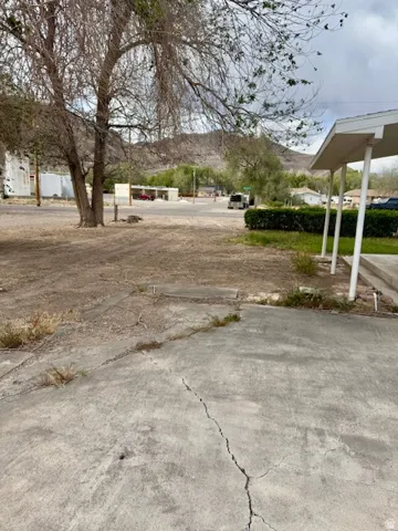 Concrete driveway with visible cracking, bordered by a dirt and gravel landscape