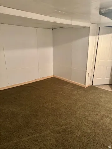 Brown carpet flooring with white baseboards, white paneled walls, and a white ceiling with exposed beams