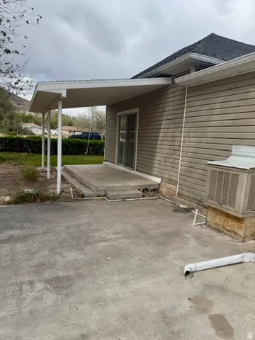 Exterior patio featuring concrete slab, attached white awning, and sliding glass door access