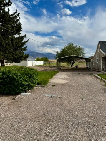 Gravel driveway leading to a metal carport structure, offering covered parking