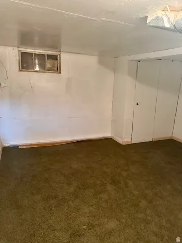 Room featuring green carpeting, white walls, and a window opening