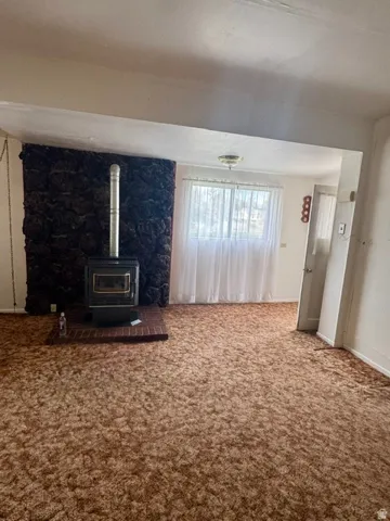 Living area with a stone-clad wall, wood-burning stove on a brick hearth, and wall-to-wall carpeting