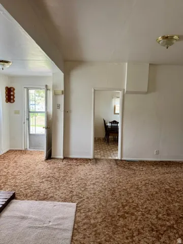 Spacious room featuring broadloom carpeting, white painted walls, and a ceiling-mounted light fixture