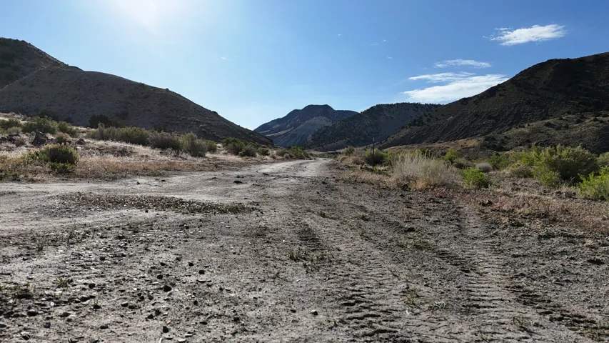 Expansive terrain featuring a dirt pathway and surrounding hills
