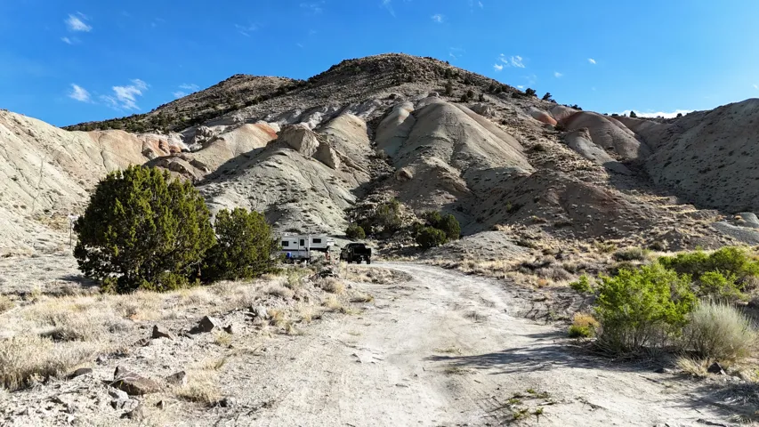 Expansive mountainous terrain featuring varied rock formations and scattered desert vegetation