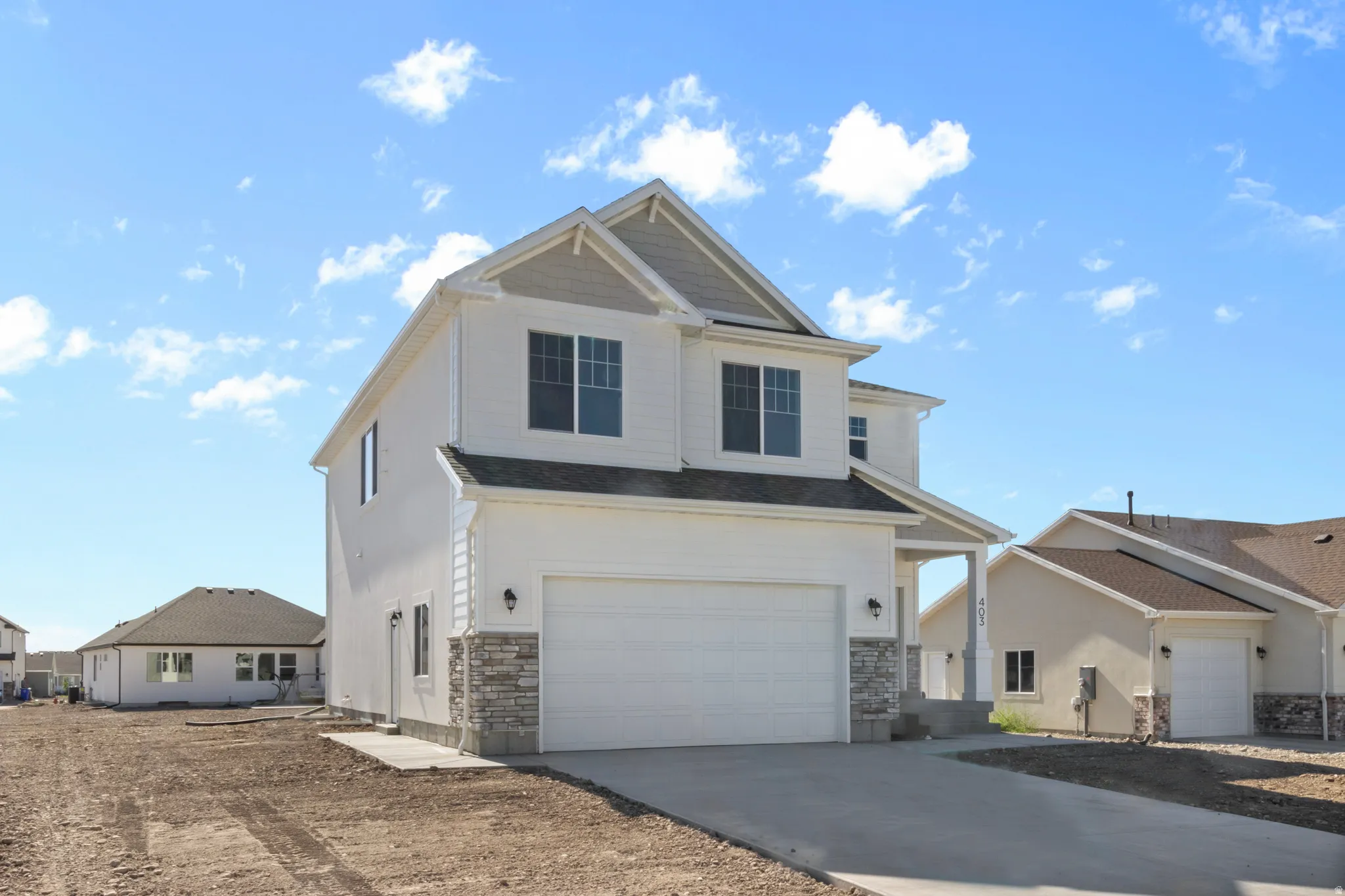 Contemporary two-story residence featuring a two-car garage, stone veneer accents, and a covered entryway