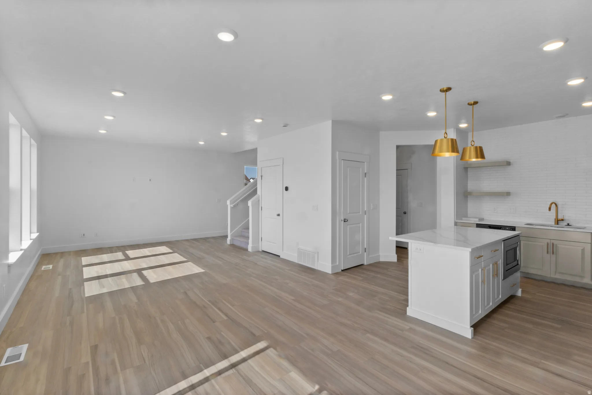 Open-concept living space featuring wood-finish flooring, recessed lighting, and a kitchen island with stone countertops