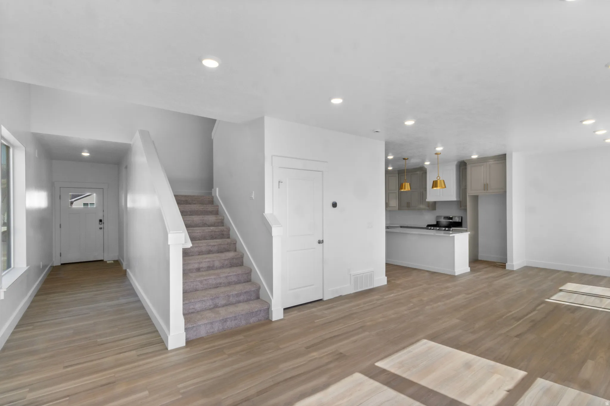 Open-concept living area featuring light wood-finish flooring, recessed lighting, and a neutral color palette