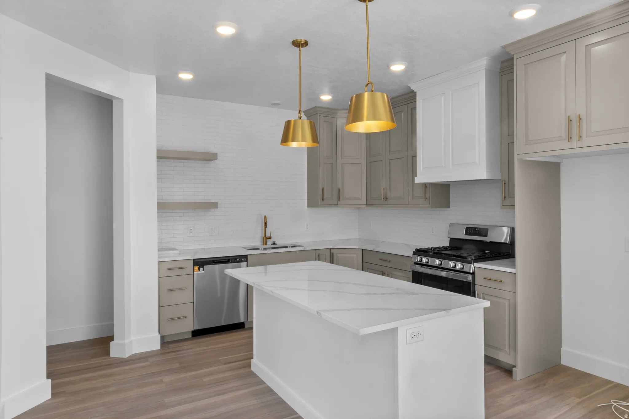 Kitchen featuring a center island with a stone countertop, stainless steel appliances, a white subway tile backsplash, recessed lighting, and dual brass pendant lights