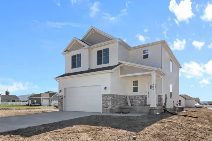 Contemporary two-story residence featuring a two-car garage, stone veneer accents, and a covered front porch with pillar supports