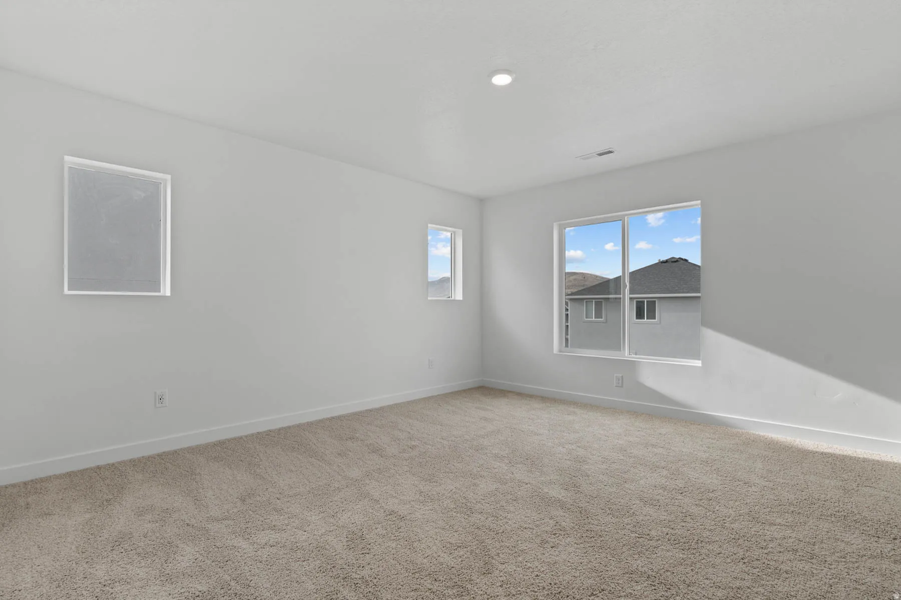 Spacious room featuring neutral carpet flooring, white painted walls, and white trim