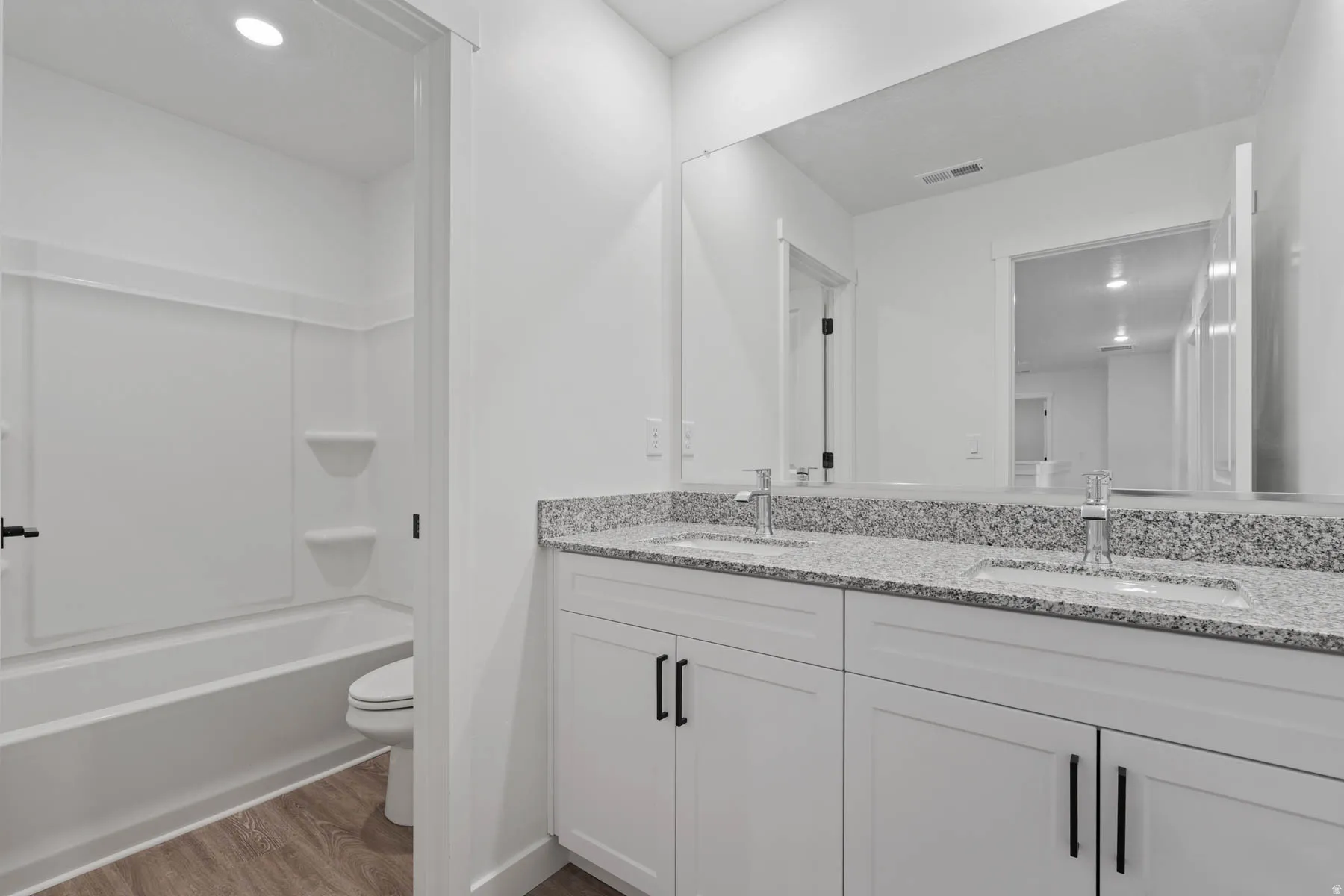 Bathroom featuring a double vanity with stone countertops, undermount sinks, and contemporary fixtures