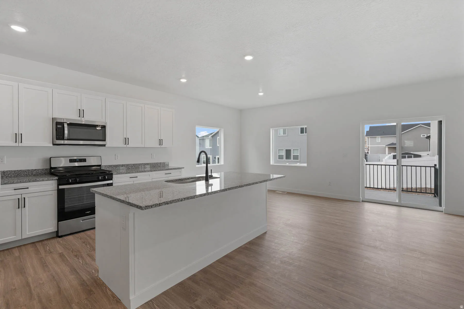 Modern kitchen featuring white cabinetry, stainless steel appliances, and granite countertops
