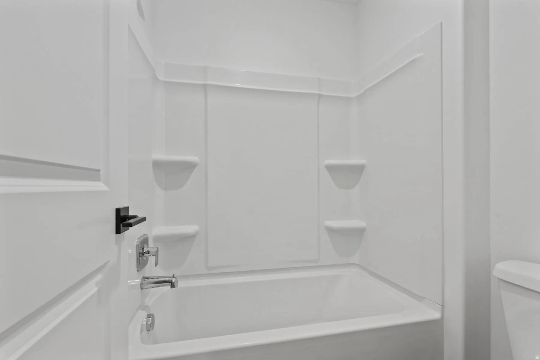 White acrylic bathtub and shower surround with integrated shelving