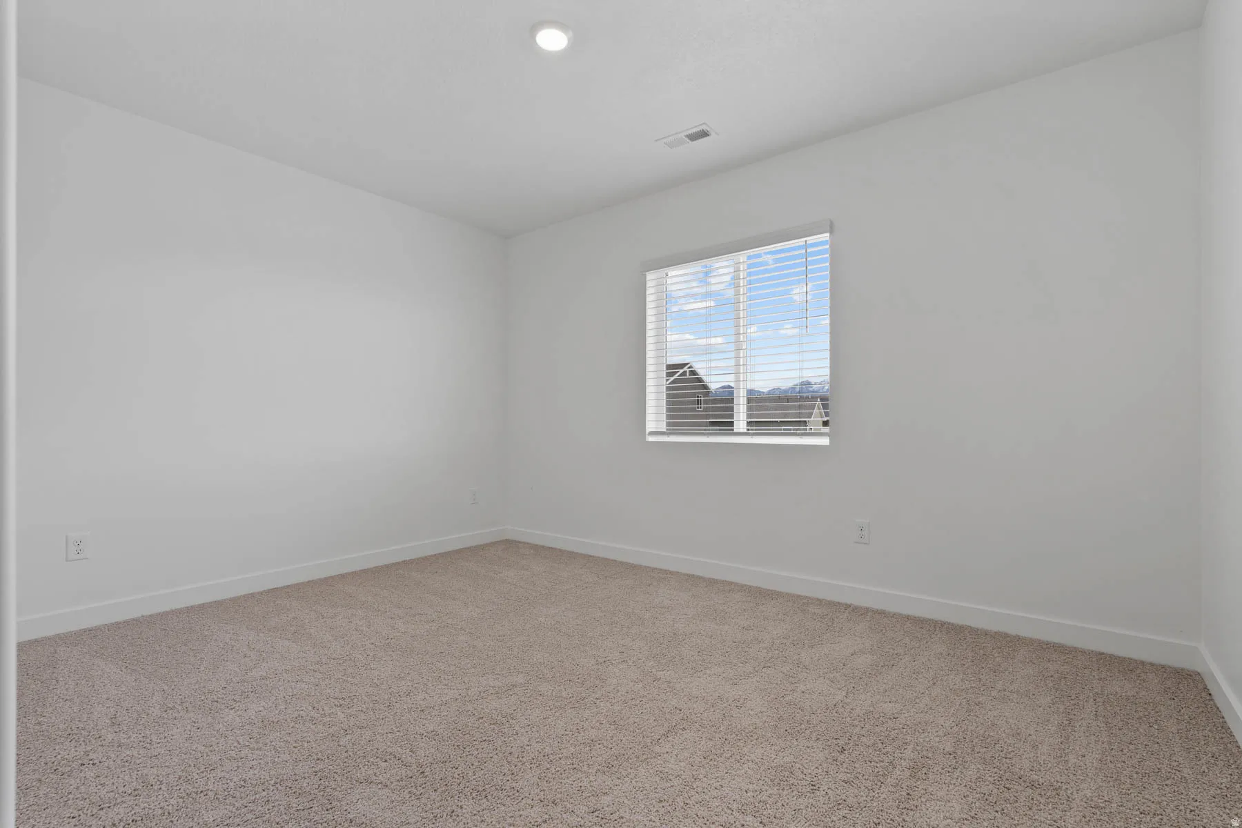 Carpeted interior space featuring a window with blinds, recessed ceiling lighting, and white walls with matching baseboards