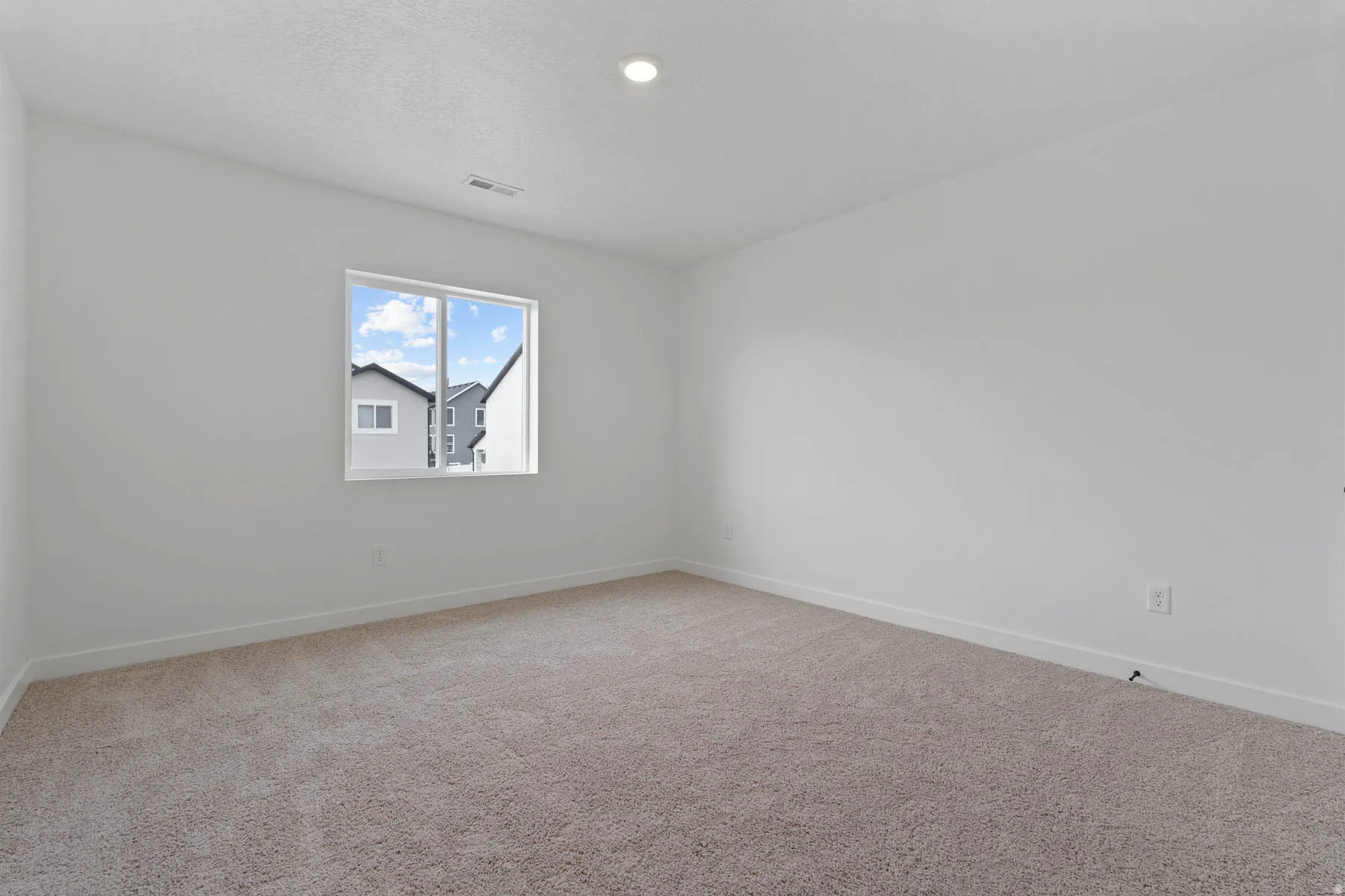 White-painted walls with recessed lighting, a single window, white trim, and neutral carpeting