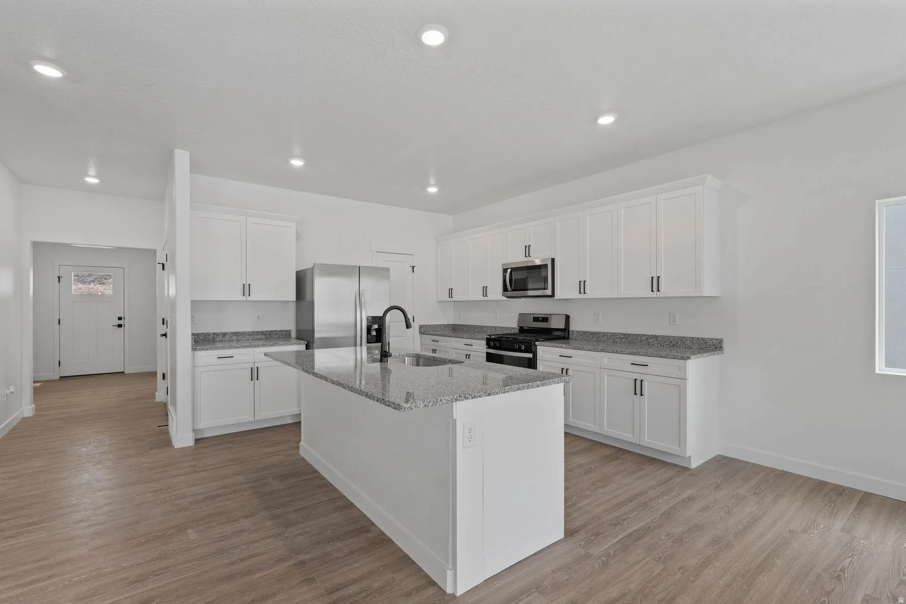 Contemporary kitchen featuring white cabinetry, granite countertops, and stainless steel appliances
