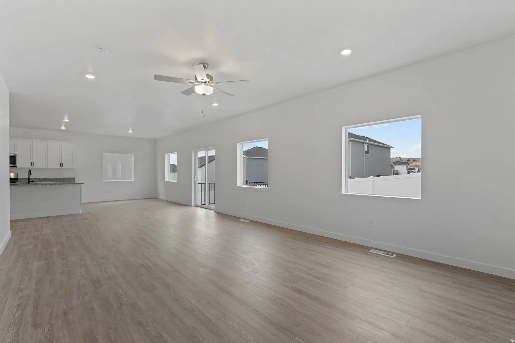 Expansive open-concept living space featuring wood-finish flooring, recessed lighting, and a ceiling fan