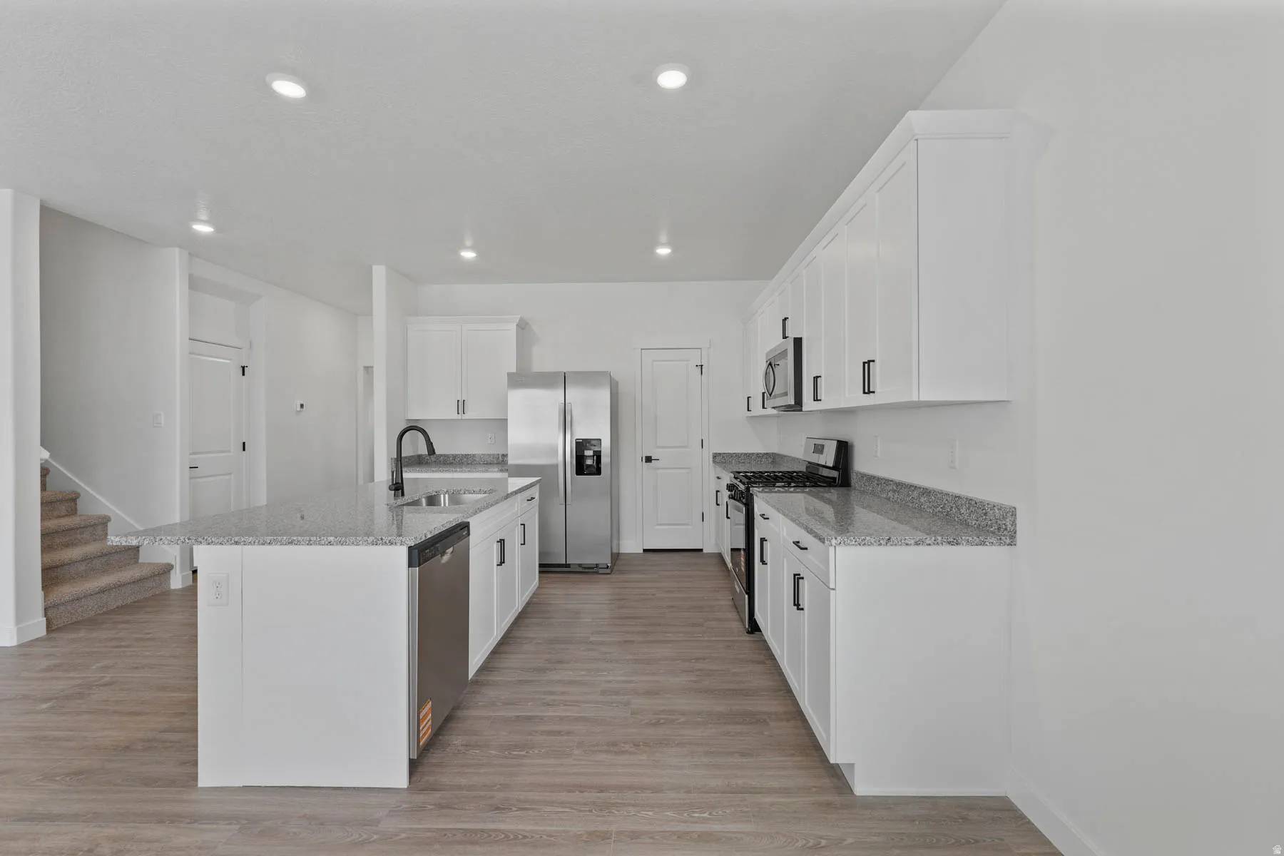 Modern kitchen featuring white cabinetry, granite countertops, and stainless steel appliances
