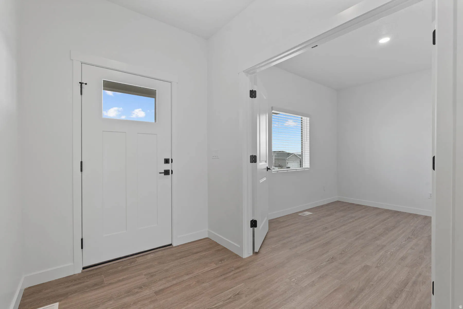 Entryway with a white paneled door featuring a clear glass insert and matte black hardware