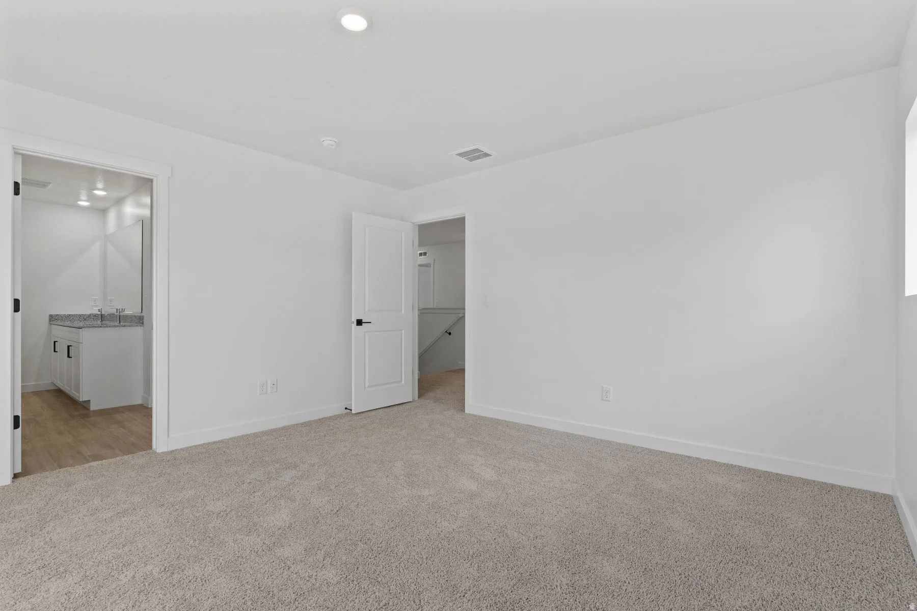Spacious room featuring neutral carpeting and white walls