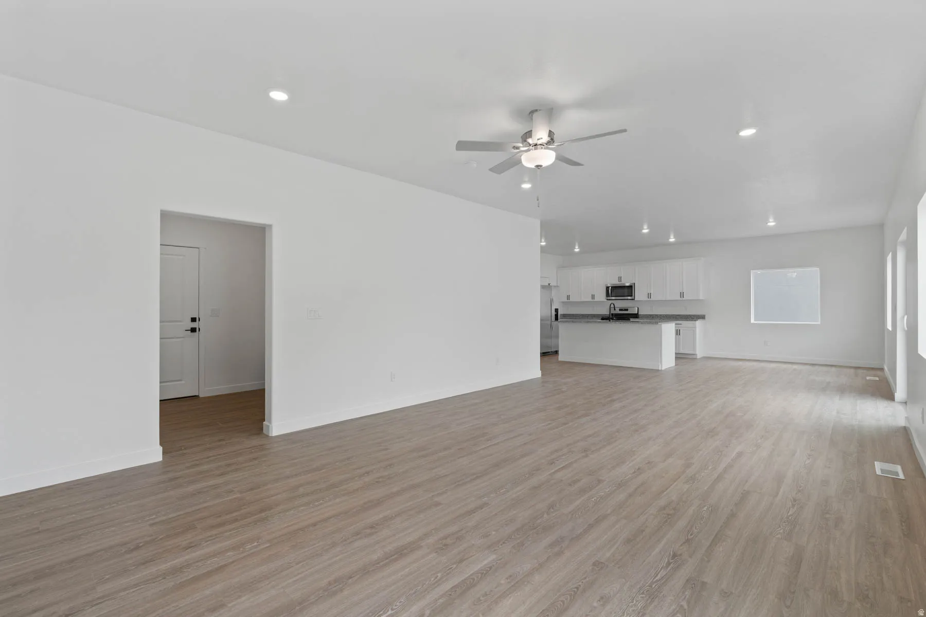 Open-concept living space featuring wood-finish flooring, recessed lighting, and a ceiling fan