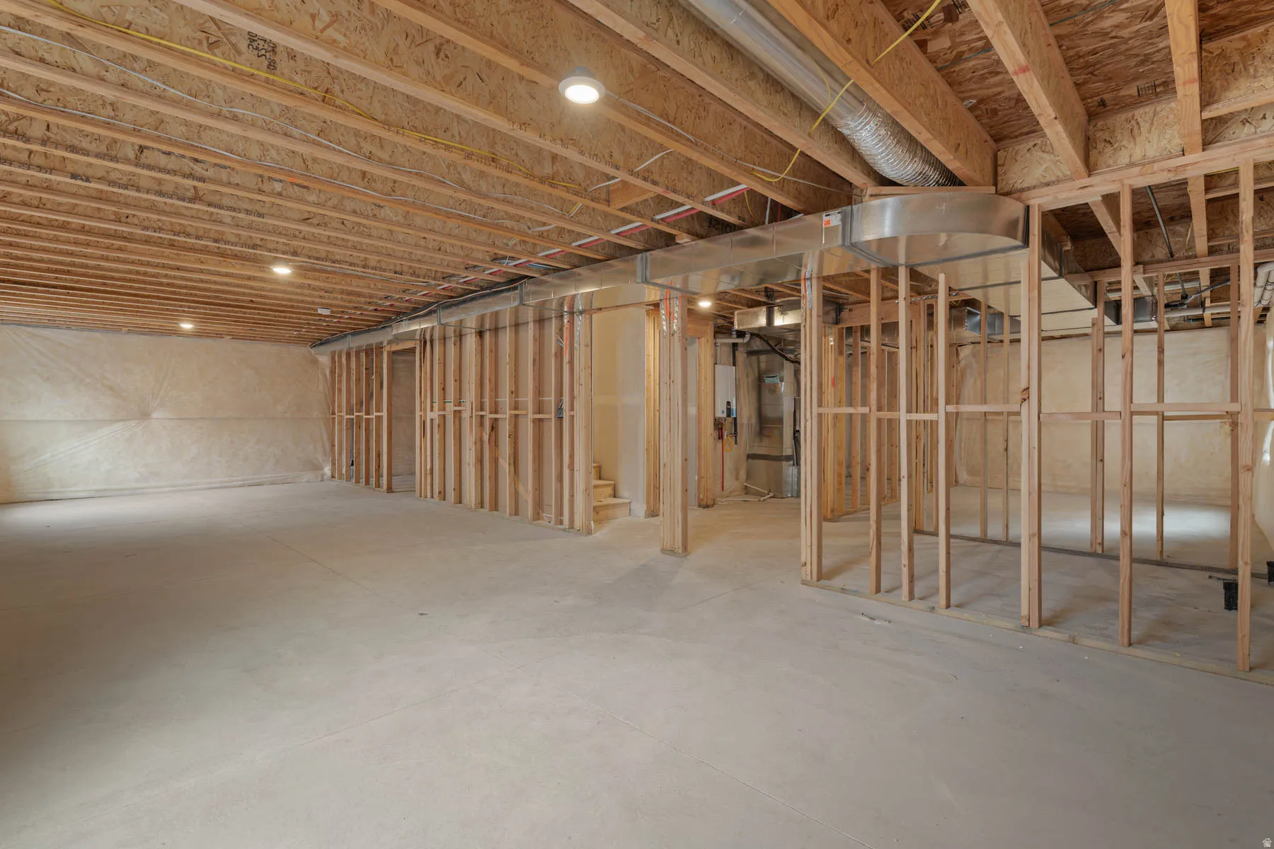 Unfinished basement with exposed wood framing, concrete flooring, recessed lighting, and visible HVAC ductwork