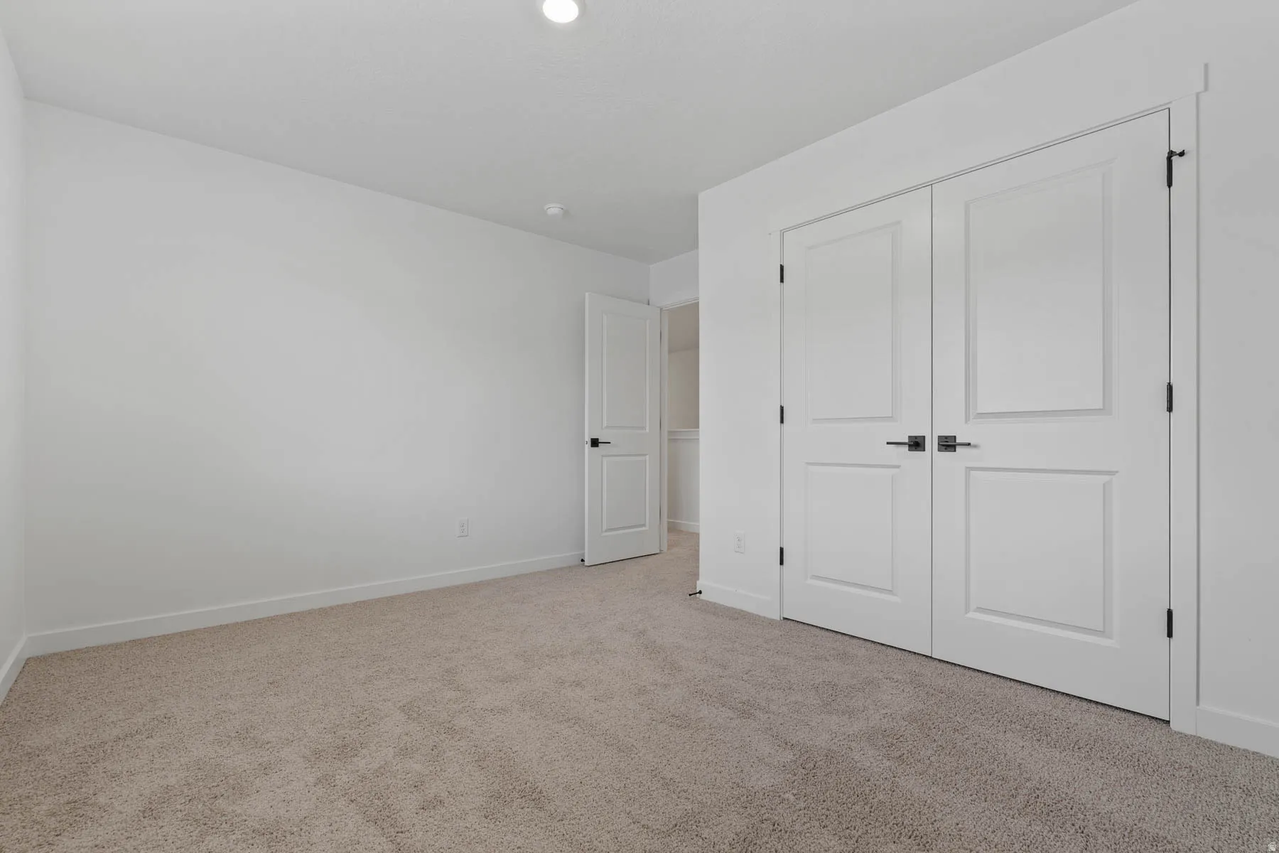 Bright interior space featuring light-toned carpeting and white walls