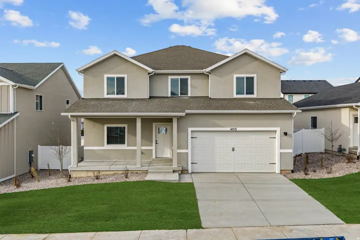 Two-story stucco exterior featuring a covered front porch, an attached garage, a concrete driveway, and a manicured lawn