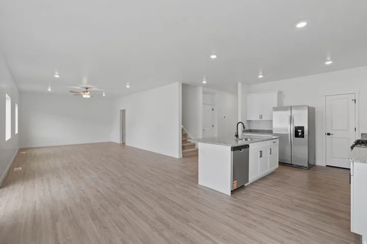 Contemporary kitchen featuring a center island with sink, stainless steel appliances, white cabinetry, and granite countertops