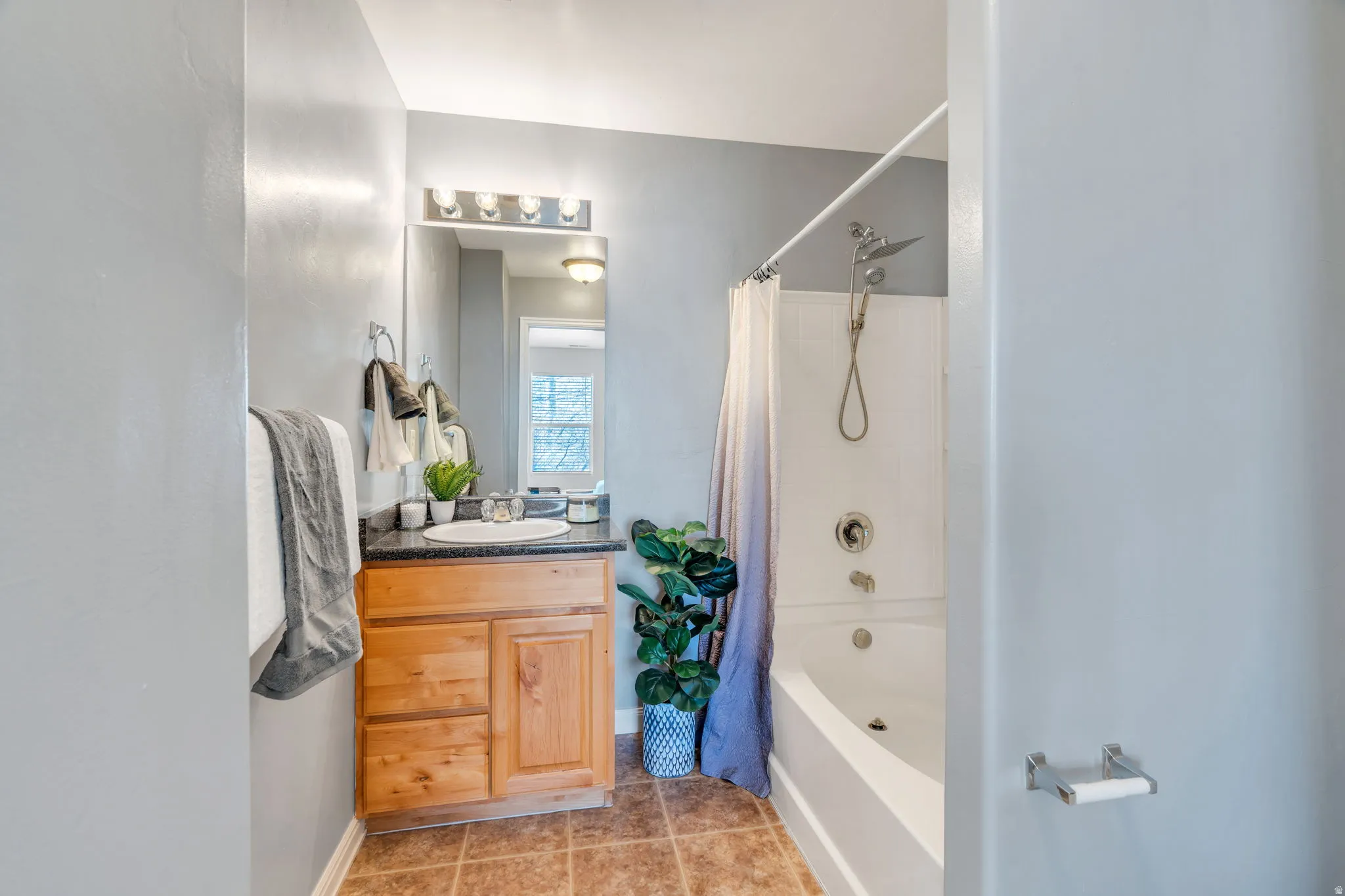 Full bathroom featuring vanity, shower / tub combo with curtain, and light tile patterned floors