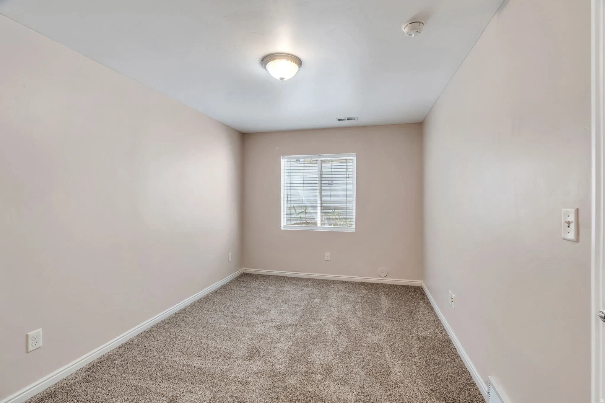 Empty room featuring carpet and a smoke detector