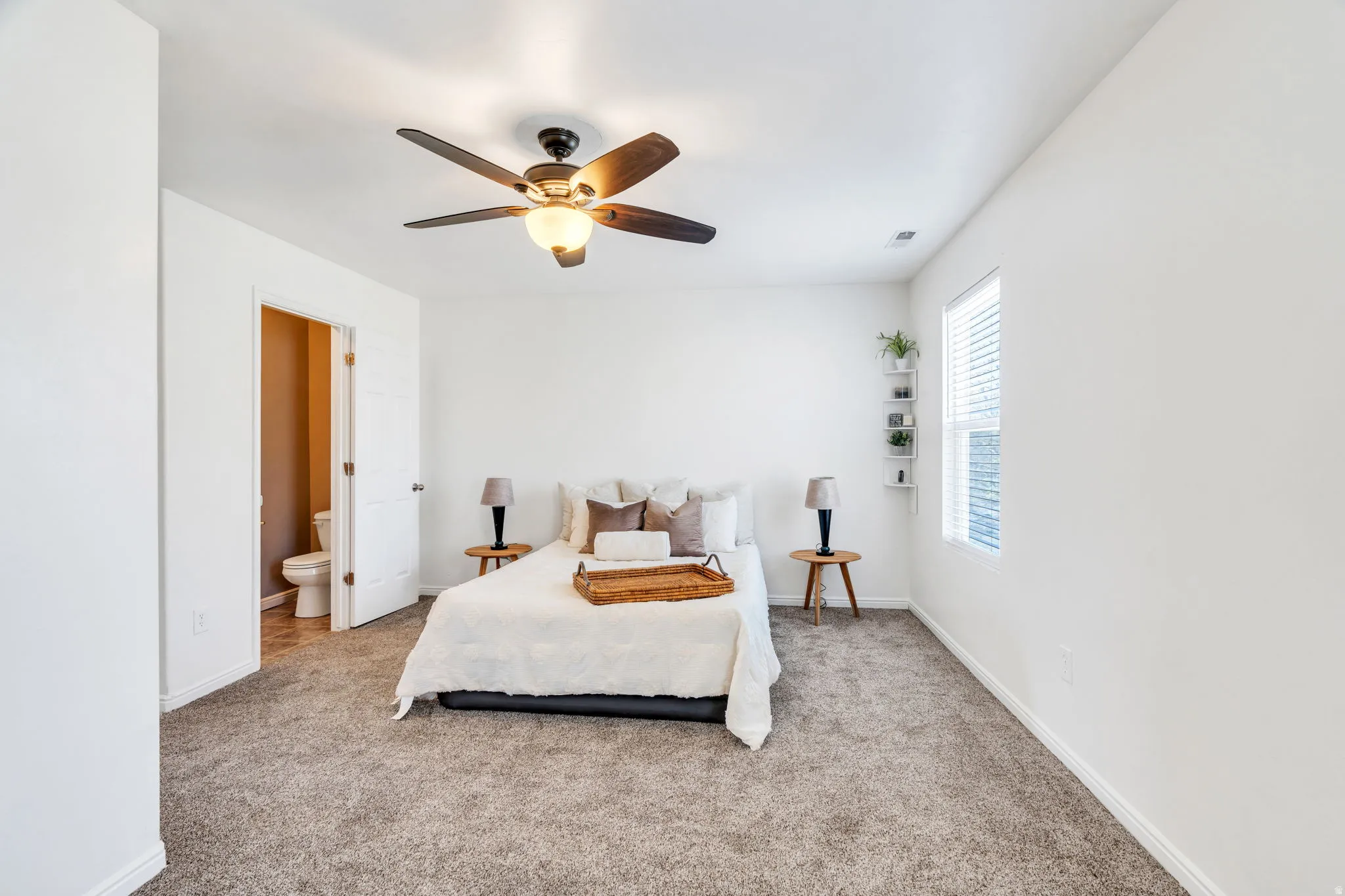 Bedroom with carpet flooring, ceiling fan, and connected bathroom