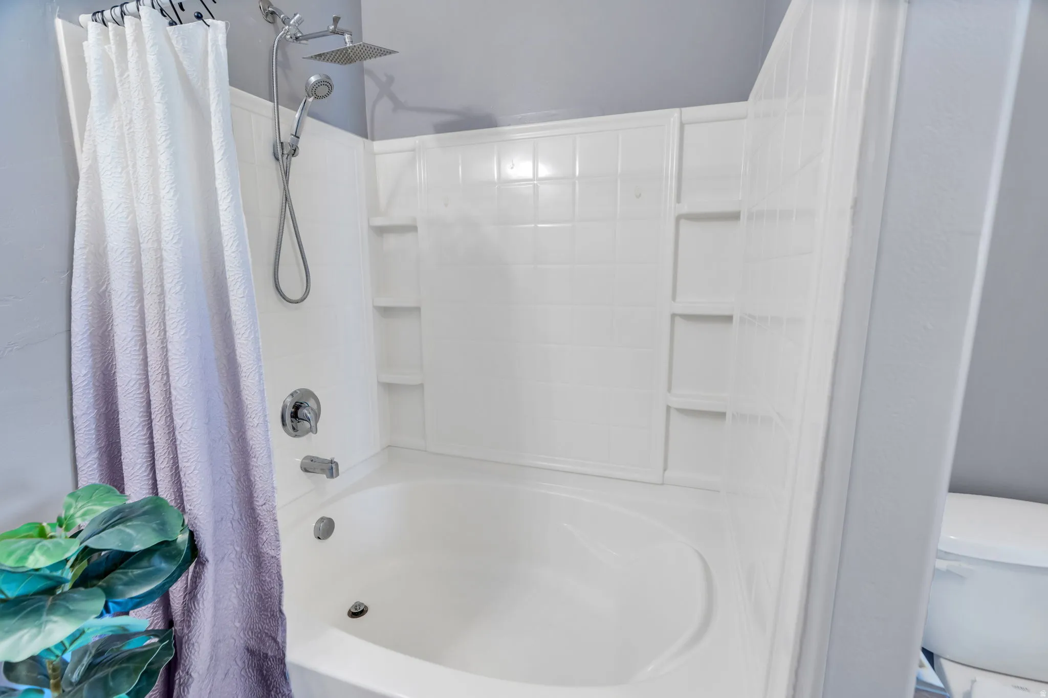Bathroom featuring toilet and shower / bath combo with shower curtain