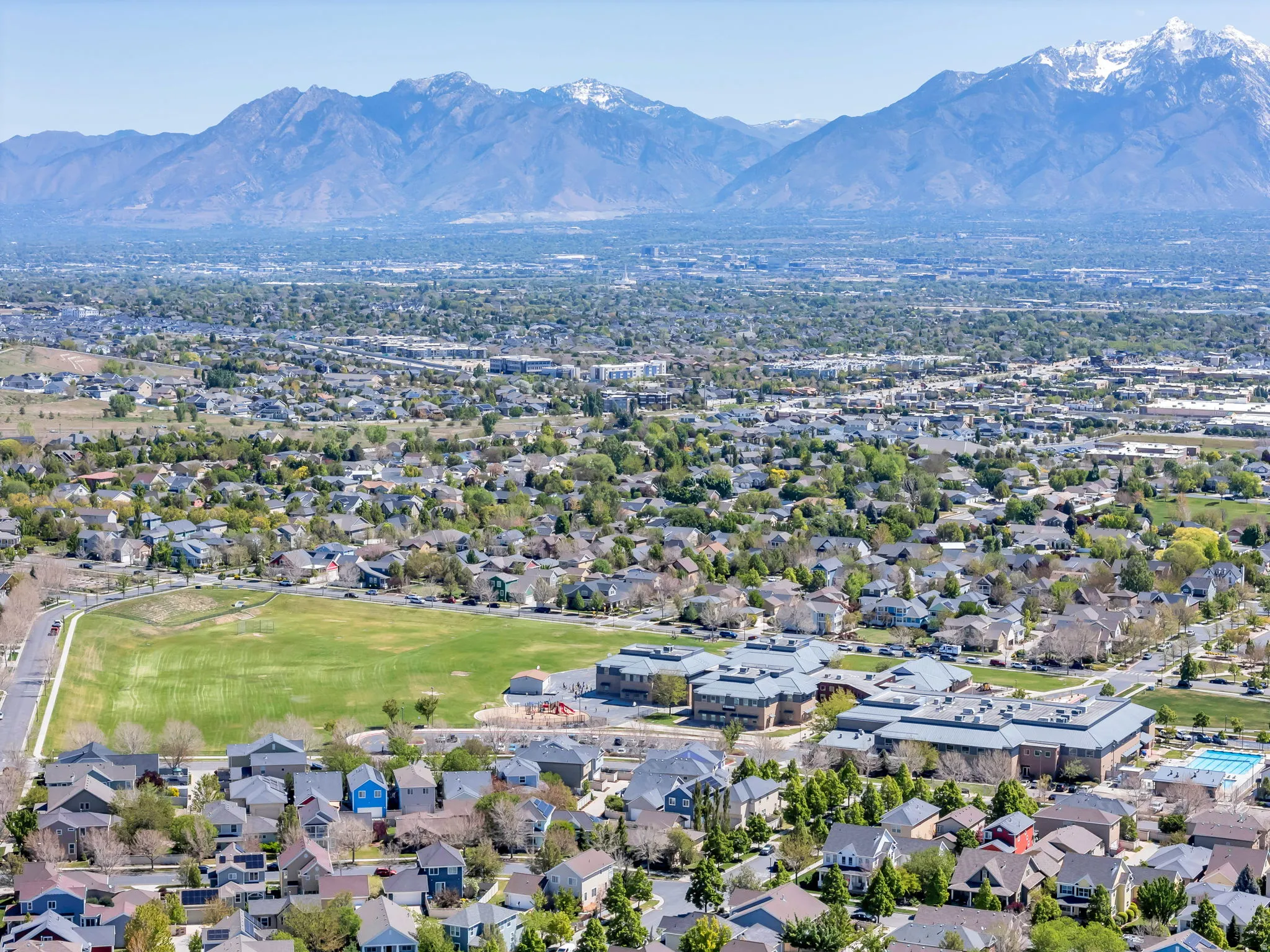 Aerial perspective of suburban area featuring a mountain backdrop and a golf course
