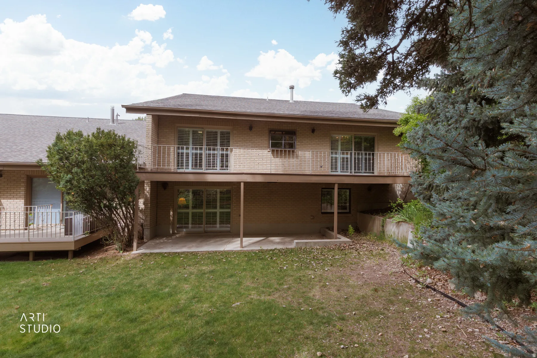 Rear exterior featuring a brick facade, dual-level outdoor spaces, and a ground-level patio