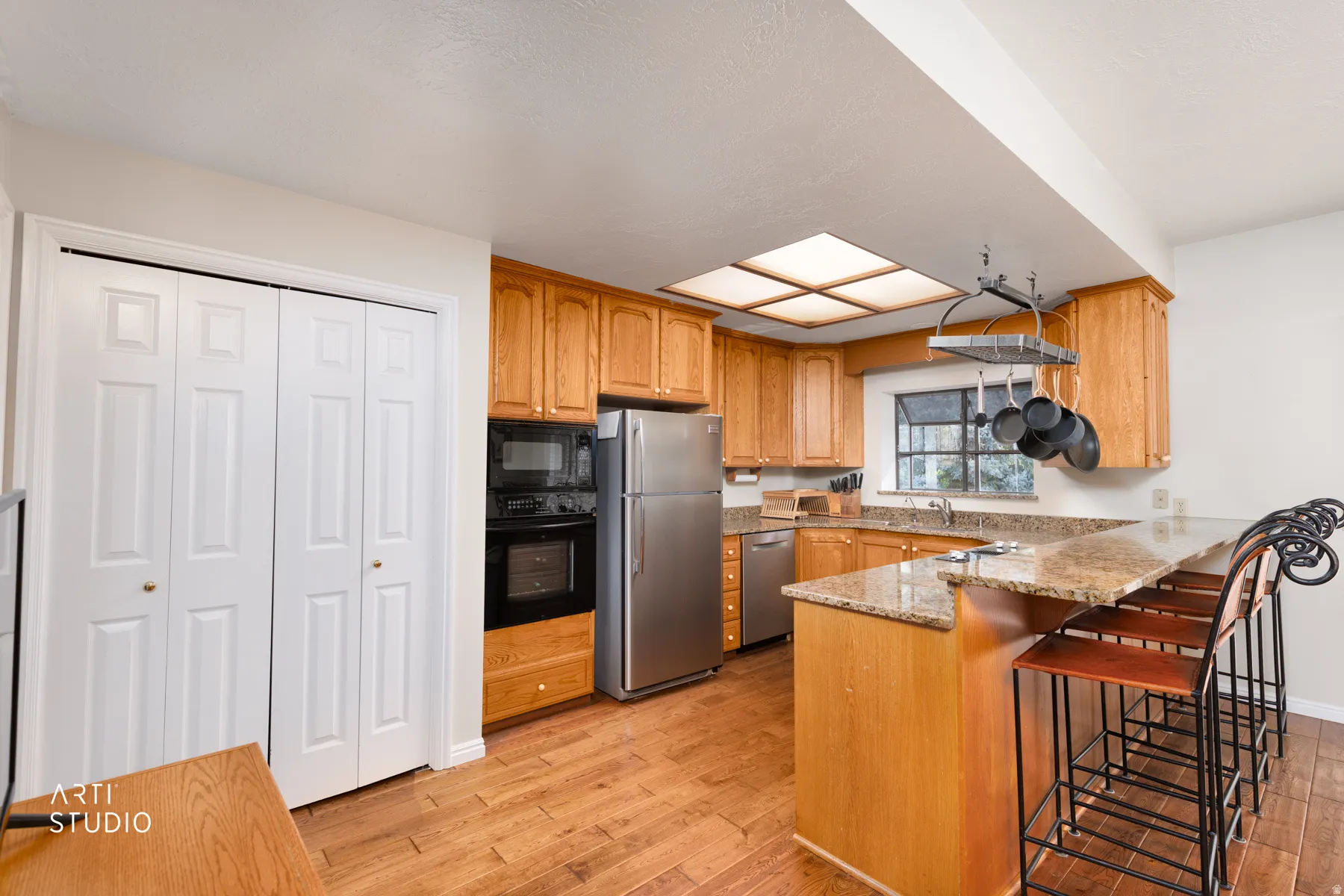 Kitchen featuring wood cabinetry, granite countertops, and wood-finish flooring