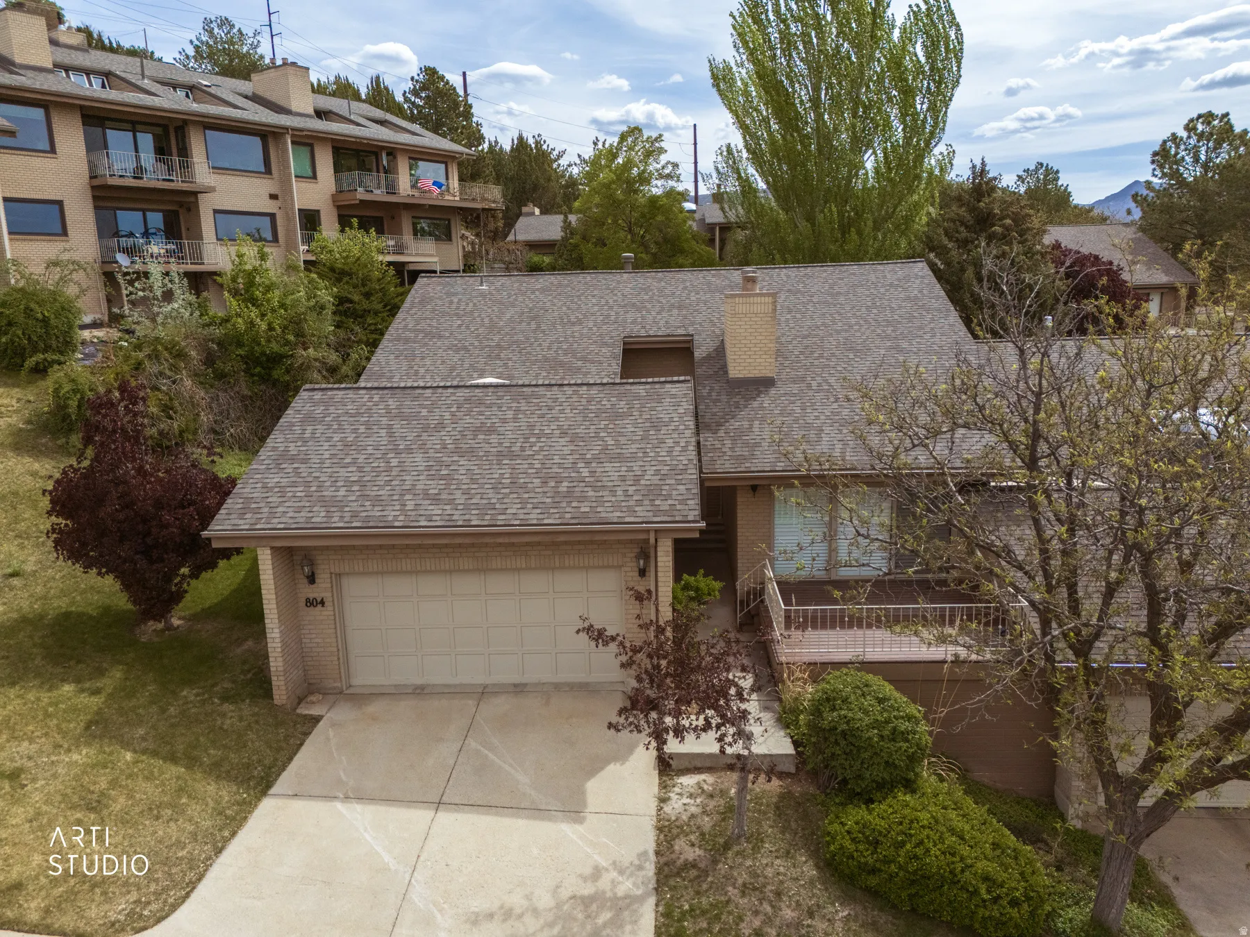 Elevasted view of front of residence featuring a prominent front-facing two-car garage, an asphalt shingle roof, and brick exterior accents