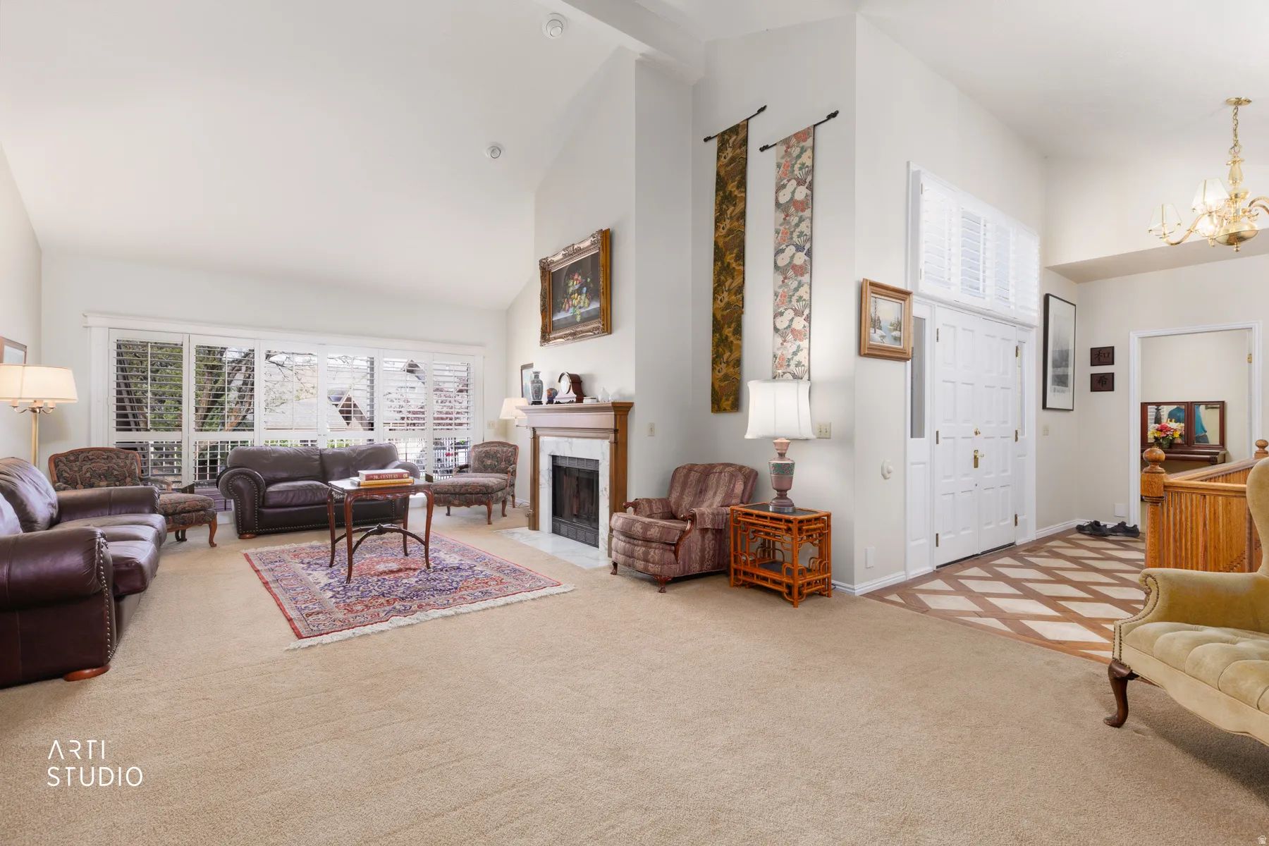Spacious living area featuring vaulted ceilings, a fireplace with a wood mantle and tile surround, large windows with plantation shutters, and a wood-finish flooring entryway