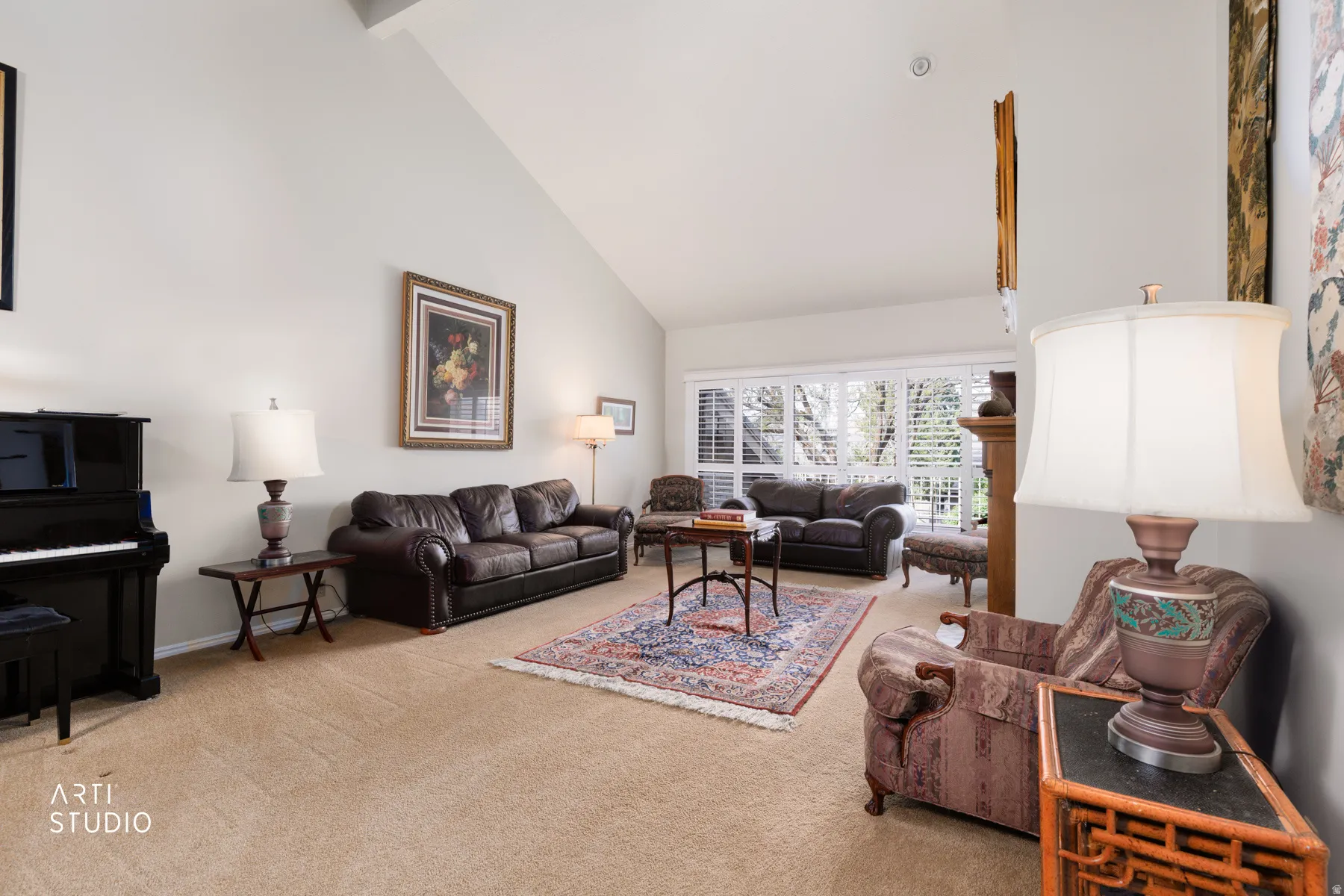 Spacious living area featuring a vaulted ceiling and light beige carpet