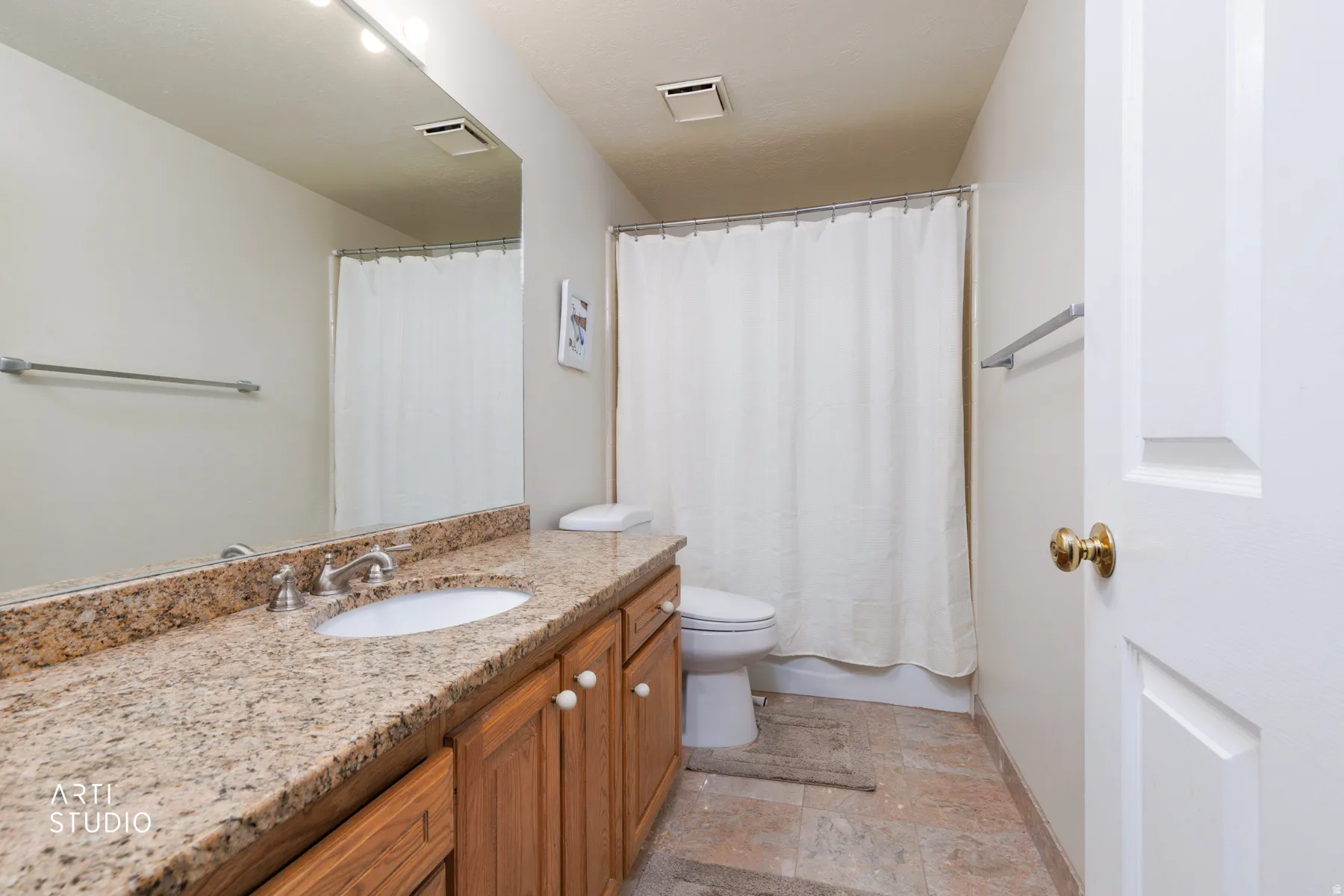 Bathroom vanity featuring a light-toned countertop, undermount sink, and wood-finish cabinetry