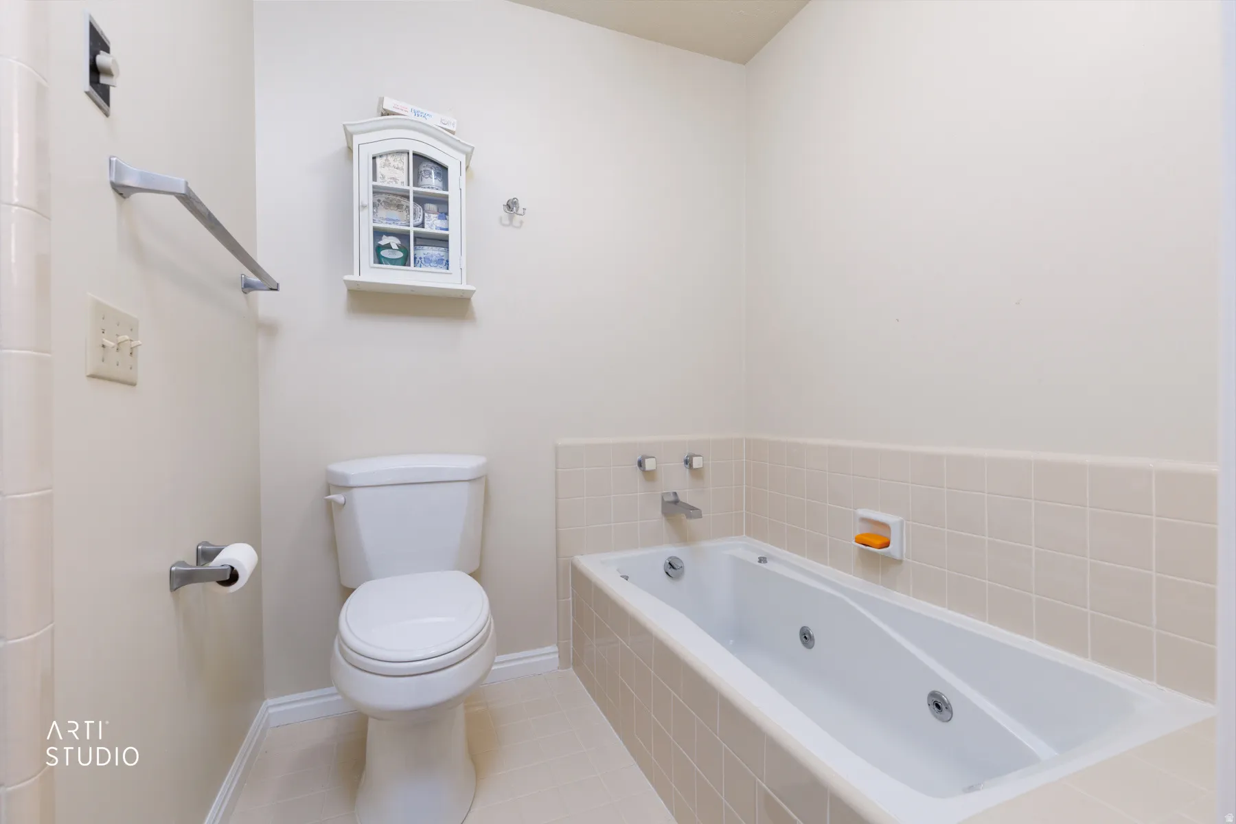 Master bathroom featuring a white toilet, jetted bathtub, tiled surround, and neutral wall tones