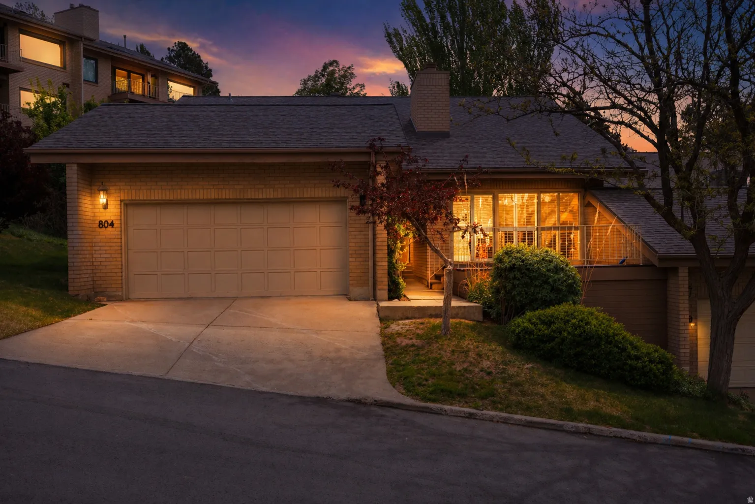 Twighlight view of front of property showing entry walk, front deck and concrete driveway.