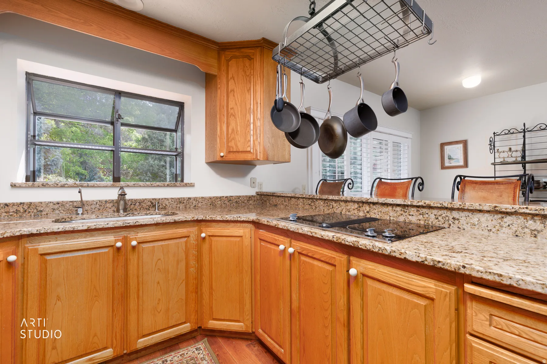 Kitchen featuring wood cabinetry, light-toned speckled countertops, a built-in cooktop, and a stainless steel sink with a single-handle faucet