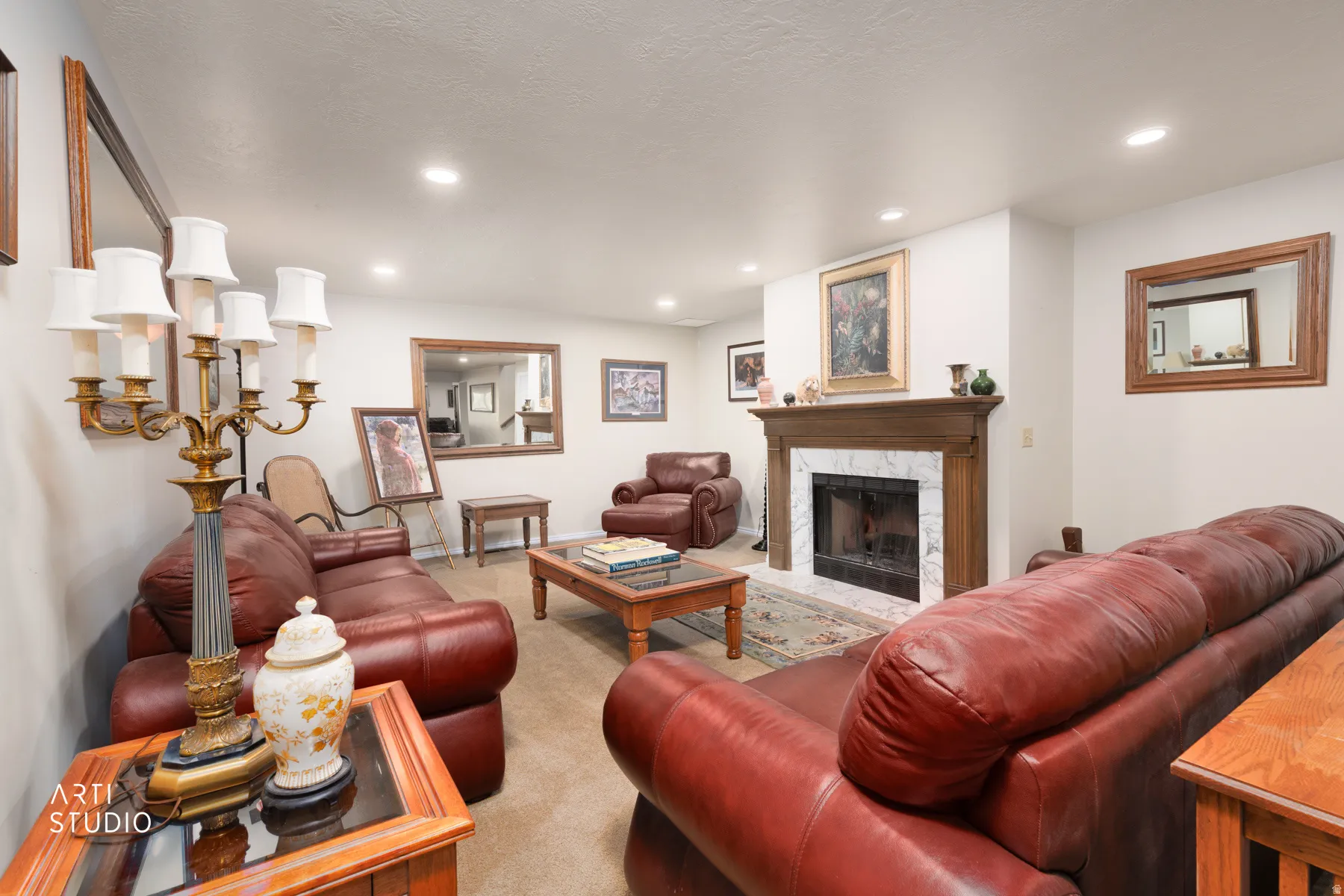 Downstairs family room featuring a traditional wood mantel fireplace with a marble surround and hearth, recessed ceiling lighting, and wall-mounted mirrors