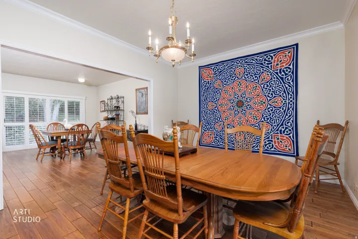 Dining area featuring wood-finish flooring, a chandelier, and crown molding
