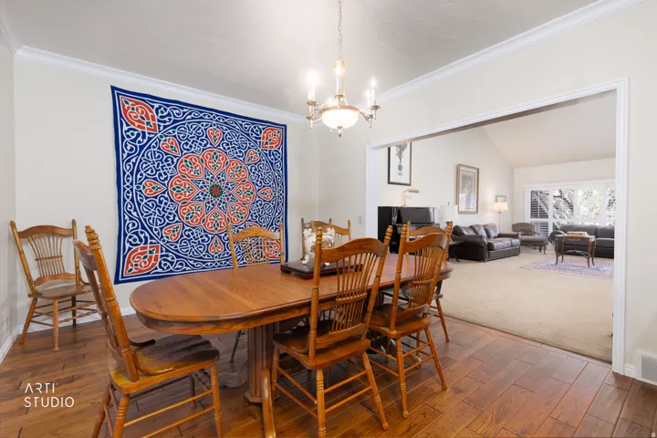 Dining area featuring wood-finish flooring, a chandelier, and crown molding